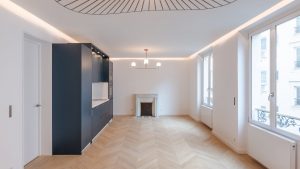 Grande pièce avec meuble bleu et parquet à chevron